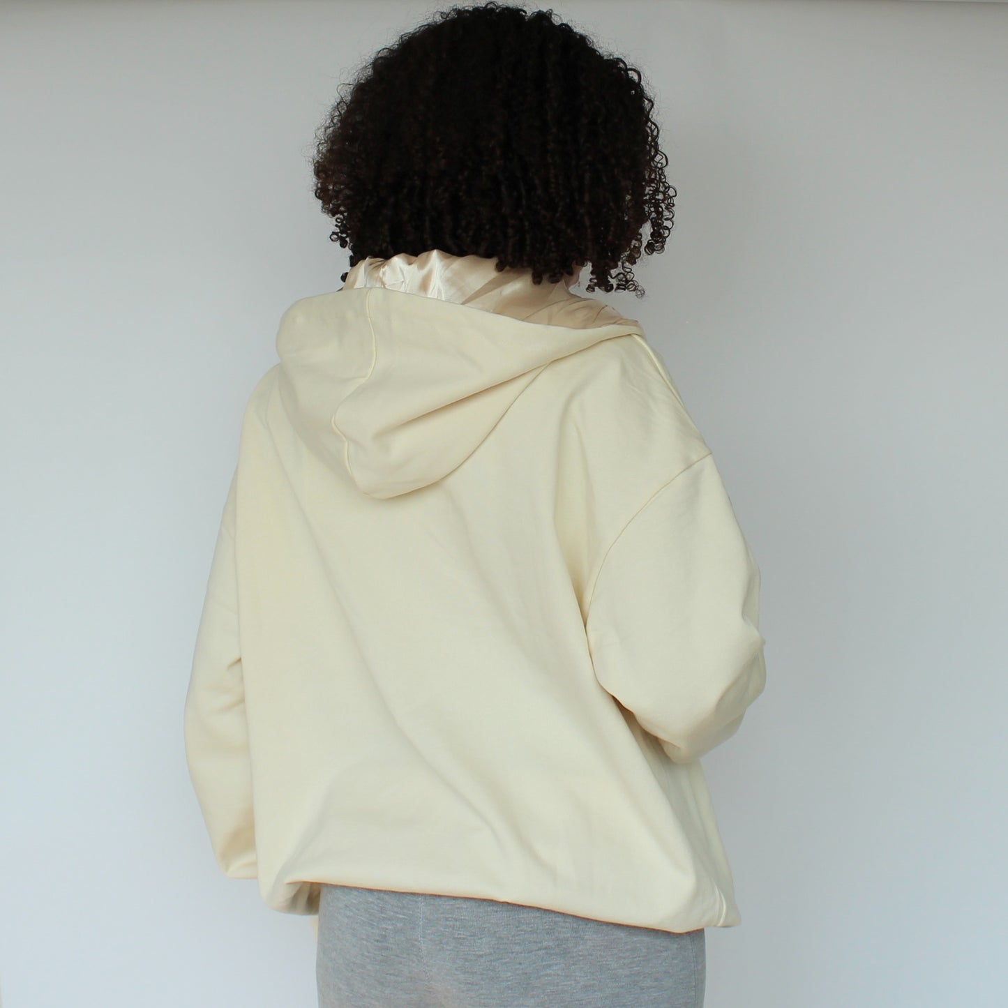 Back view of the Miae Beige Satin-Lined Zip Hoodie on model, showing flattering fit and satin-lined hood.