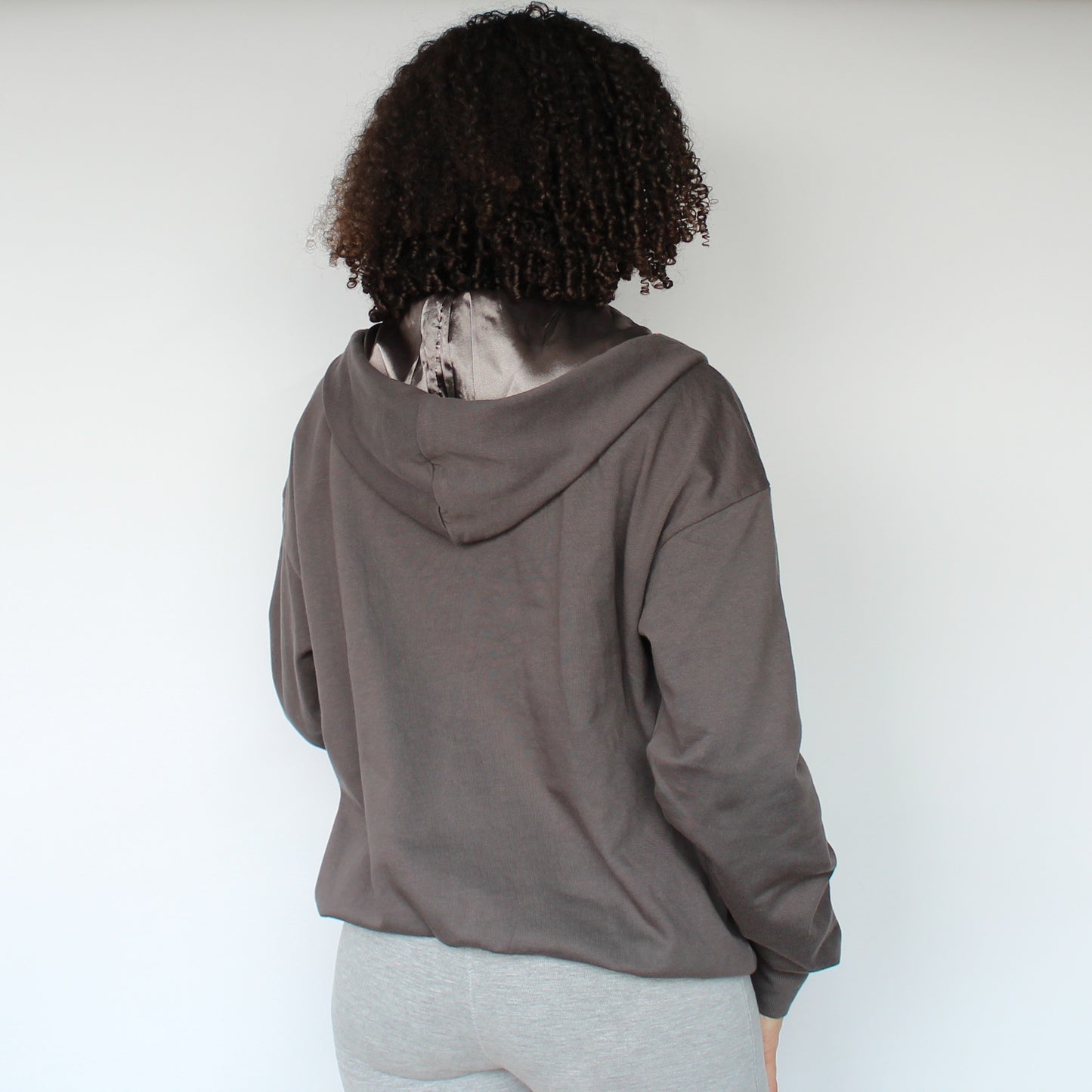 Back view of the Miae Charcoal Satin-Lined Zip Hoodie on model, featuring a protective satin hood and clean finish