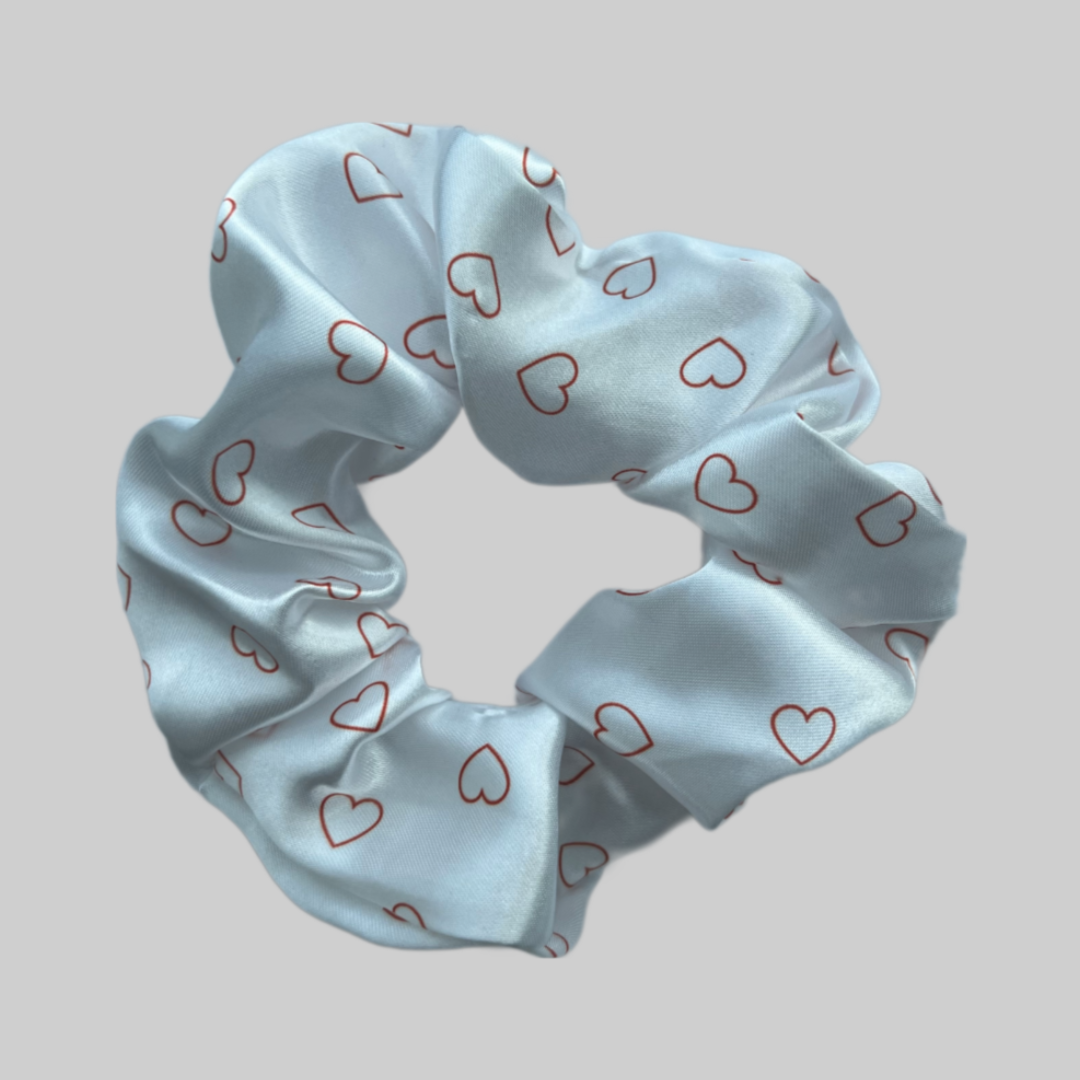 Flat lay of the Miae Satin Scrunchie with minimalist love hearts, a subtle and elegant hair accessory designed to reduce frizz and breakage.