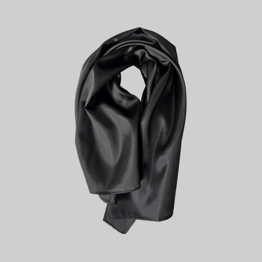Flat lay of the Miae Black Satin Hair Scarf, a sleek and frizz-reducing accessory designed to protect curly and textured hair.