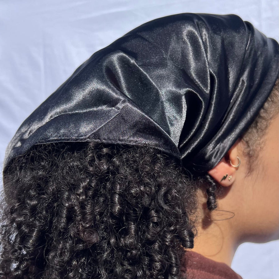 Model wearing the Miae Black Satin Hair Scarf, styled over curly hair to reduce frizz and add shine, while providing a protective, moisture-locking effect.