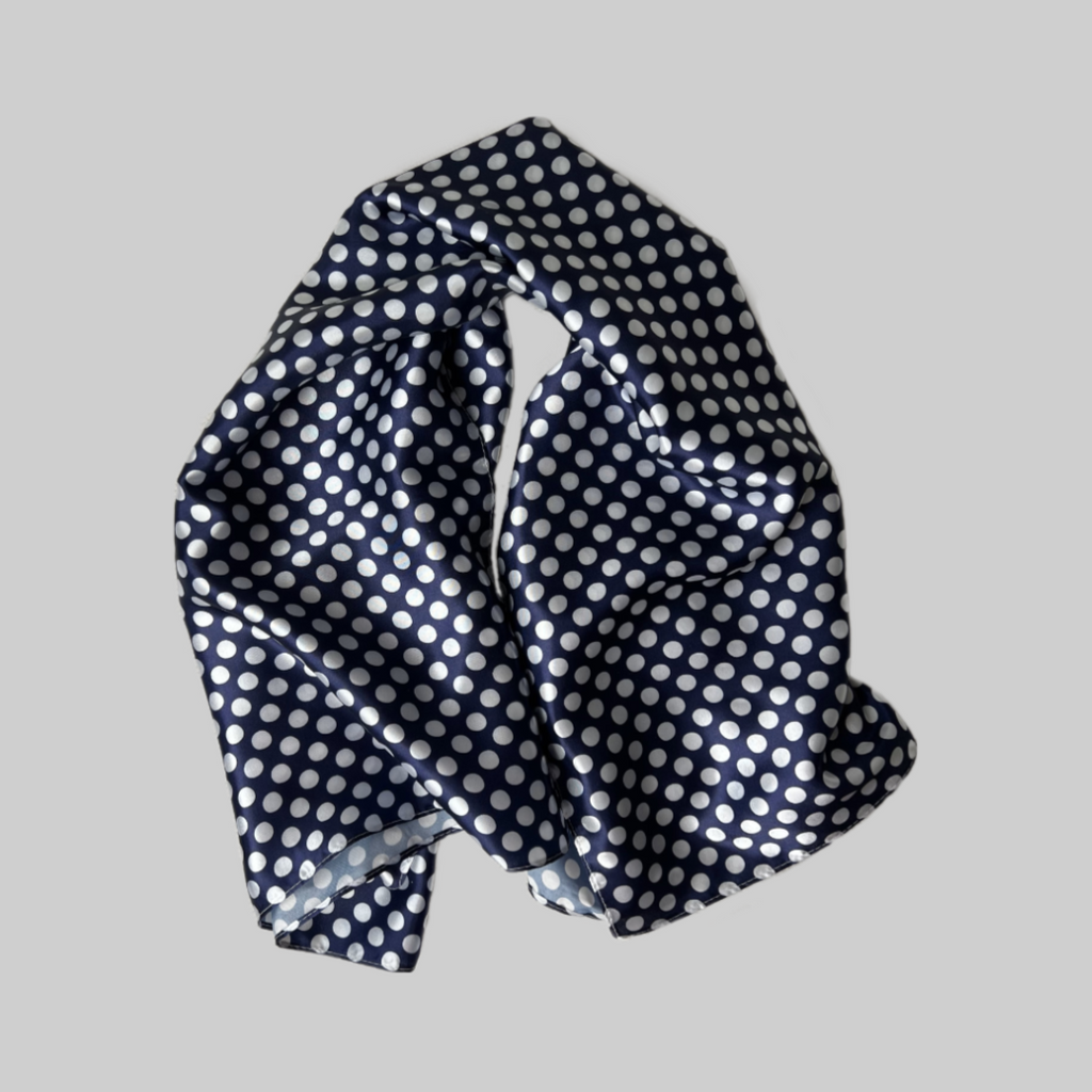 Flat lay of the Miae Blue Satin Hair Scarf with white polka dots, a soft and stylish accessory designed to reduce frizz and protect natural, textured, and curly hair.