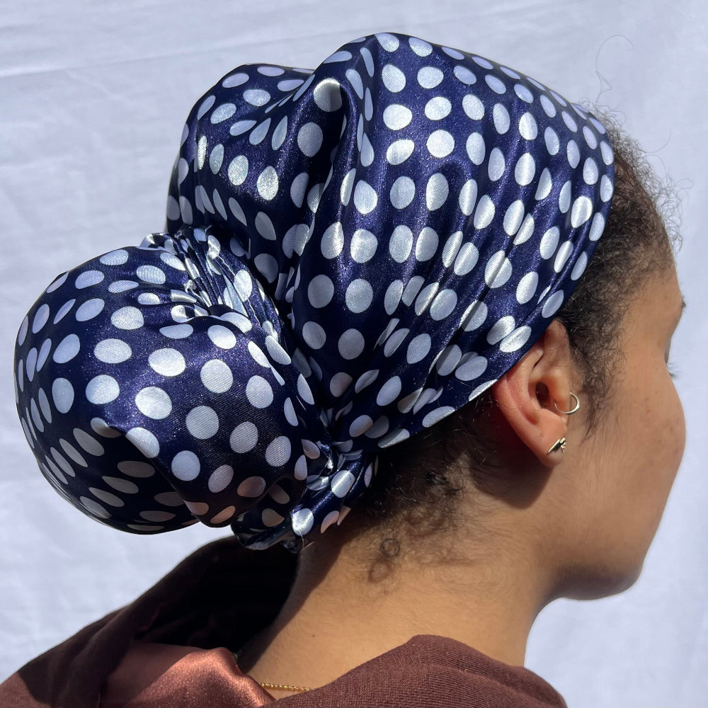 Model wearing the Miae Blue Satin Hair Scarf with white polka dots, styled elegantly on curly hair to prevent frizz and breakage.