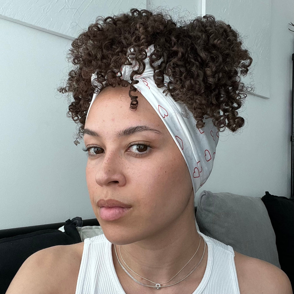 Model wearing the Miae Satin Hair Scarf with minimalist love hearts, styled over curly hair to reduce frizz and add a chic, frizz-free look.