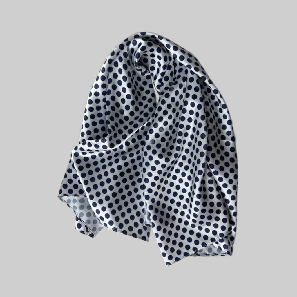 Flat lay of the Miae White Satin Hair Scarf with blue polka dots, a smooth and frizz-reducing accessory designed for curly and textured hair.