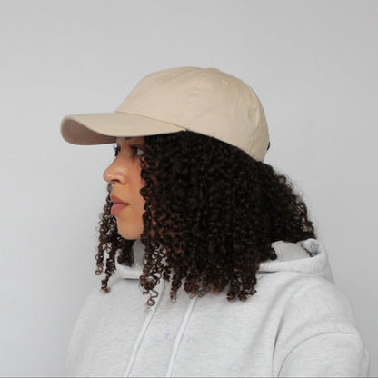 Model wearing the Miae Beige Satin-Lined Cap, an unstructured cap with a curved visor that flatters the face while protecting natural, textured, and curly hair.