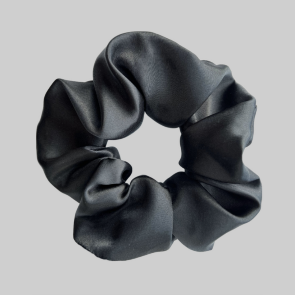 Flat lay of the Miae Black Satin Scrunchie, a sleek and frizz-reducing hair accessory for all hair types