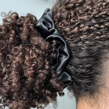 Curly ponytail styled with the Miae Black Satin Scrunchie, offering a smooth, breakage-reducing hold with a luxurious finish.