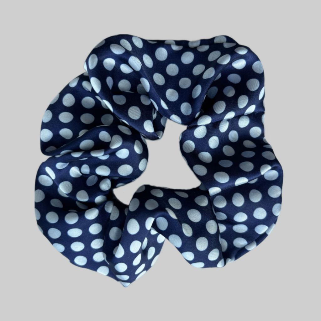 Flat lay of the Miae Blue Satin Scrunchie with white polka dots, a smooth and stylish hair accessory designed to reduce frizz and breakage.