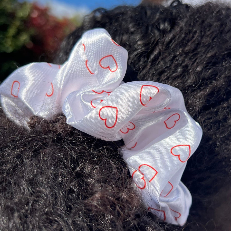 Curly hair styled in a ponytail with the Miae Satin Scrunchie featuring minimalist love hearts, offering a gentle, frizz-reducing hold.